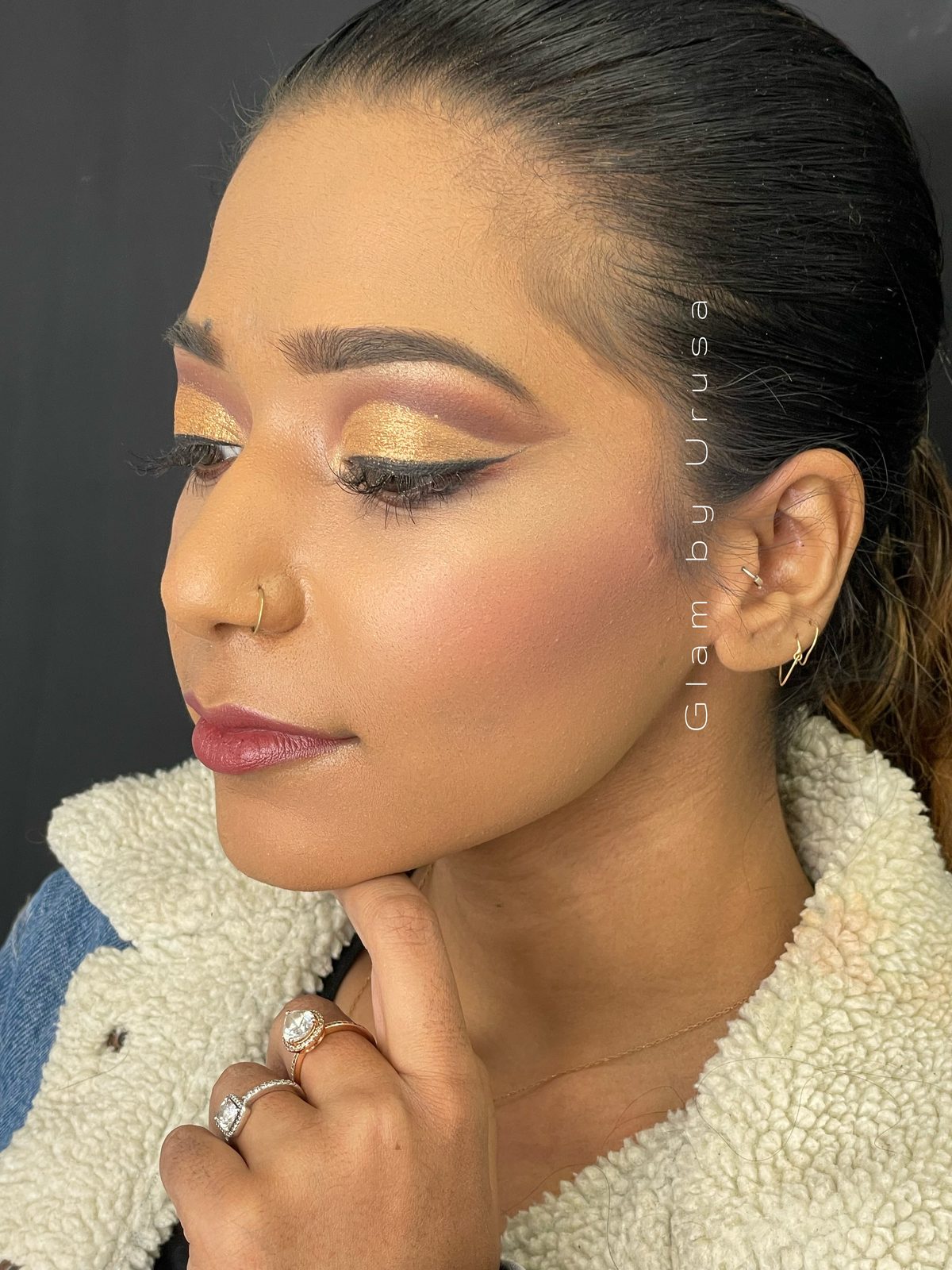 Gold cut-crease glam makeup with sharp winged liner and a berry lip for an evening event