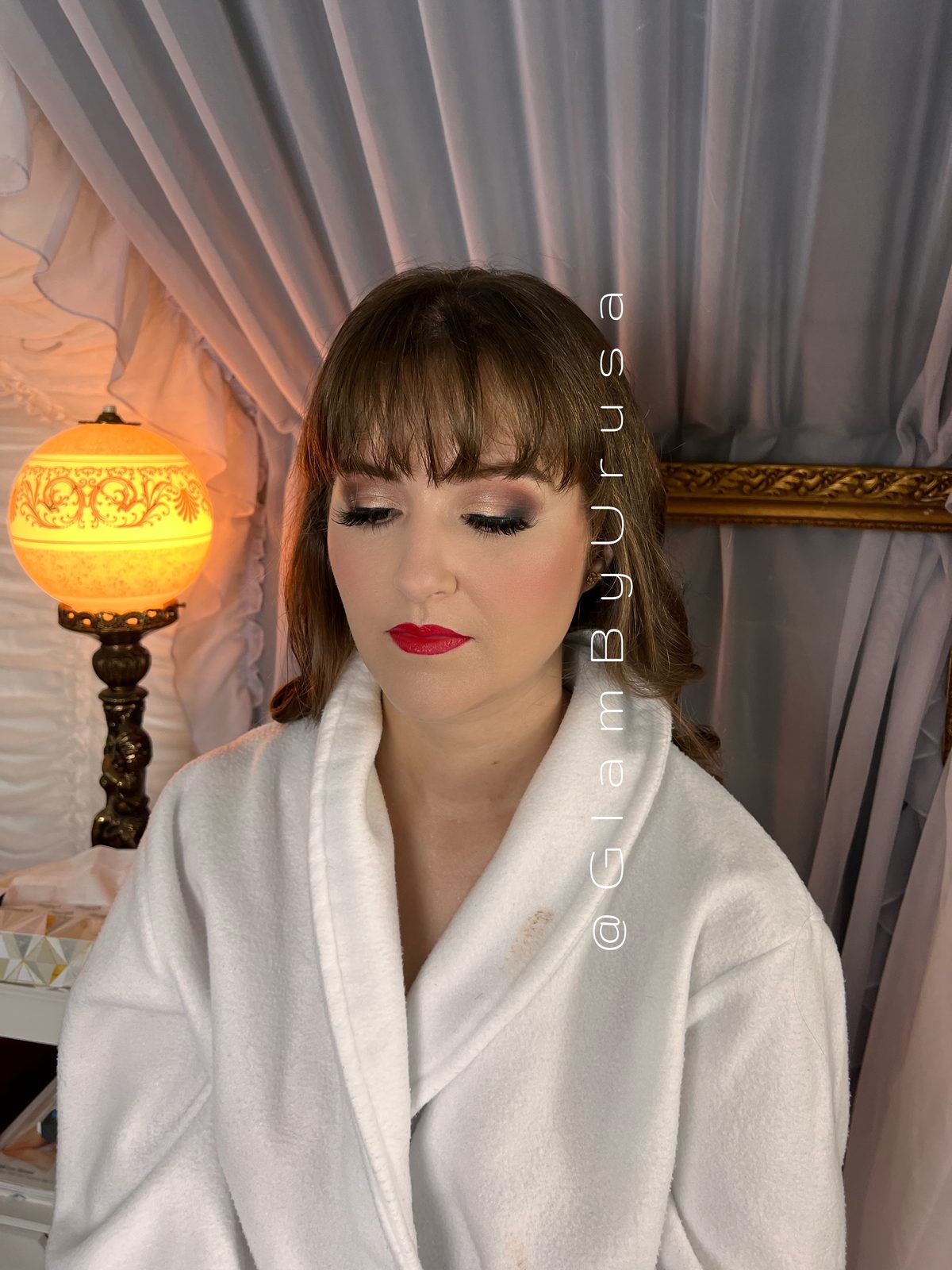 Vintage-inspired glam makeup with a classic red lip, defined lashes and curtain bangs